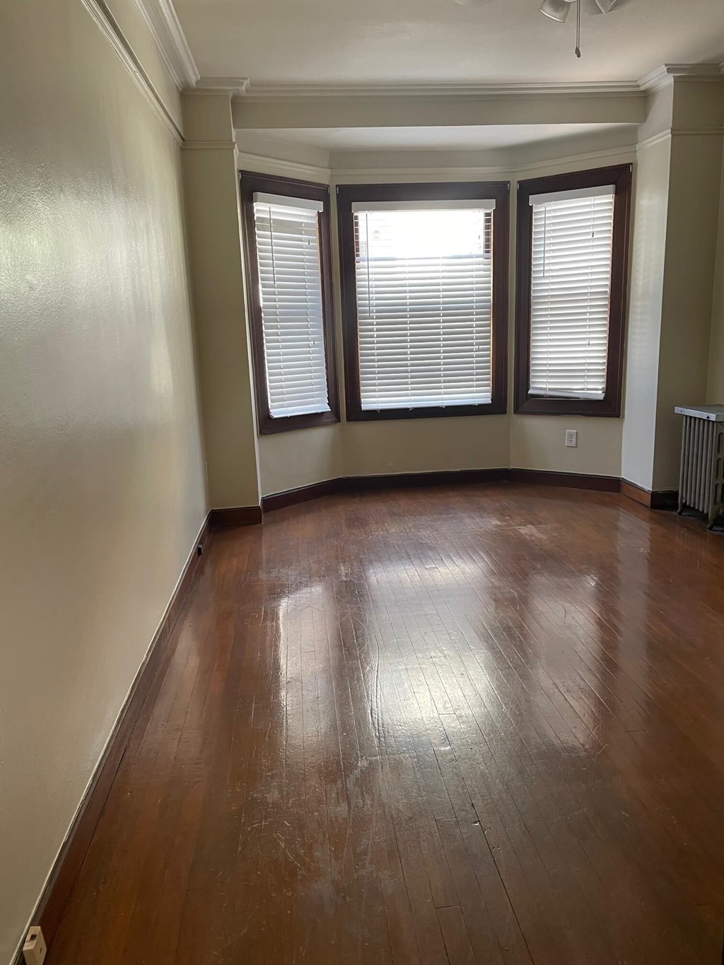 an empty living room with wooden floors and three windows